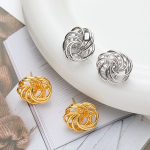 Modern intertwined bird nest stud earrings in gold and silver finish on white plate