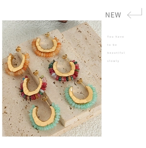 Close-up of vintage C-shape hoop earrings with green and orange natural stone beads