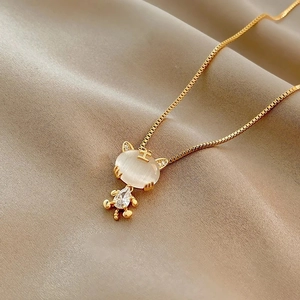 Detail shot of a gold cat pendant with opal and zircons on a wavy silk chain necklace