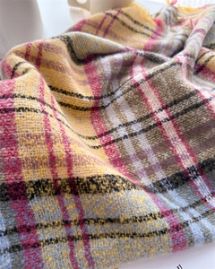 Close-up of checkered scarf showing soft wool texture and fringed edges in warm tones