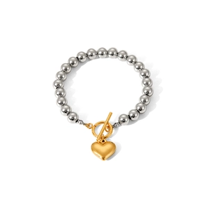 Detail of silver beaded bracelet with gold heart charm and decorative OT toggle clasp