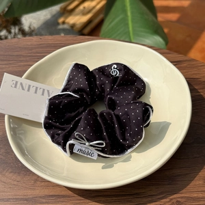 Detail of black polka dot satin scrunchie with silver musical note charm and bow