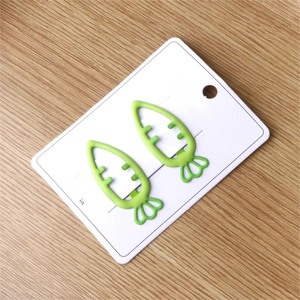 Close-up of green carrot-shaped hair clips for girls on a white display card