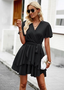 Détail d'une robe noire en ligne A avec col en V, ourlet à volants et lien à la taille