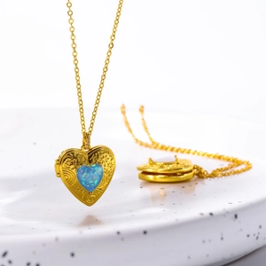 Detail of golden heart locket necklace with blue opal stone and floral engraving