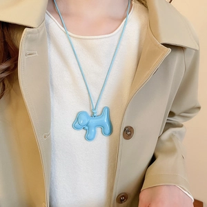 Gros plan d'un pendentif chiot bleu en émail sur un collier en cordon tressé bleu assorti