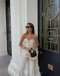 Detail of cream button-up longline vest and split hem trousers in modern outdoor street style