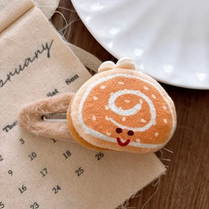 Macro detail of plush cartoon cake roll hair clip with embroidered smile and soft fabric