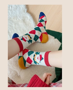 Detail of Christmas mid-calf socks with colorful argyle patterns and Santa Claus knit