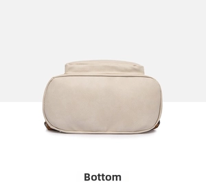 Detail view showing the oval bottom and stitching of the beige soft faux leather backpack