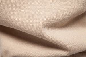 Macro view of beige knit fabric texture showing premium weaving detail and soft drape