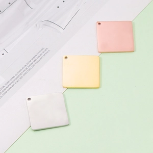 Macro detail of three square mirror polished stainless steel tags in silver, gold and rose gold