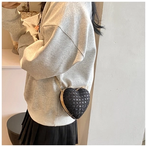 Detail of a black heart-shaped sequin crossbody bag with a gold chain strap