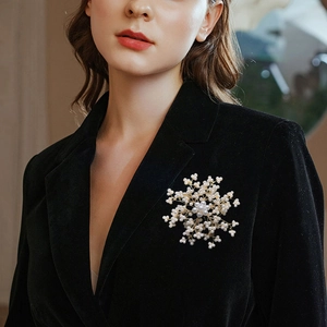 Elegant gold snowflake brooch with pearls pinned on a stylish winter coat for women
