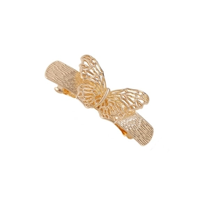 Détail de la pince à cheveux papillon évidée dorée avec une texture métallique élégante