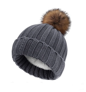 Detailed view of grey knit beanie with plush lining and brown faux fur pompom