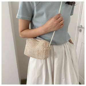 Detail of straw-style beige crossbody bag with woven texture and thin shoulder strap