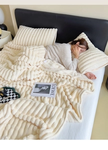 Detailed texture of thick cream-colored faux rabbit fur blanket with wave pattern design