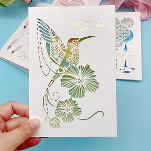 Detailed close-up of 3D laser-cut hummingbird and floral pattern on white cardstock