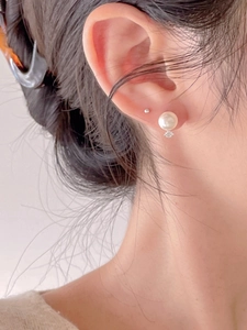 Close-up of minimalist 925 silver stud earrings with round pearl and polished silver stud