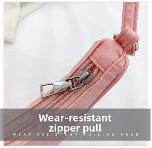 Detailed macro view of durable silver metal zipper on pink nylon crossbody bag