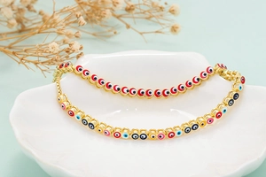 Detail of evil eye tennis bracelet with colorful enamel charms on a white ceramic dish