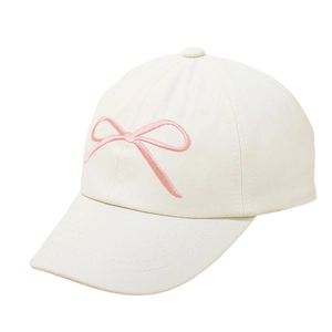 Detail of a cream baseball cap featuring a delicate pink embroidered bow design for kids