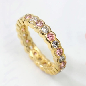 Elegant gold eternity ring with alternating pink and white gemstones in a wave band design