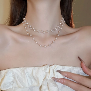 Vue détaillée d'un collier multicouche en perles et chaîne dorée sur le cou d'une femme