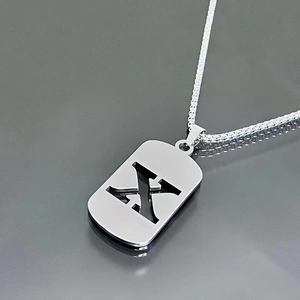 Detail view of silver stainless steel necklace with hollow rectangle letter X pendant