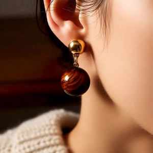 Macro shot of 18k gold plated ball earrings with brown tiger eye stone pendants