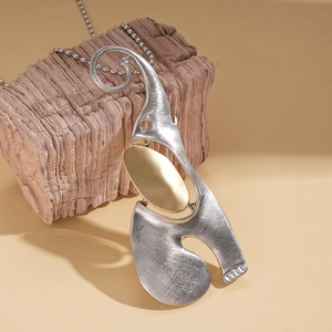 Close-up of brushed silver elephant pendant with golden oval accent and geometric design