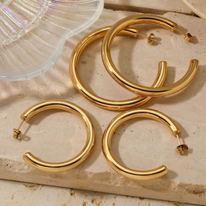 Polished chunky gold hollow C-shaped hoop earrings in two sizes on natural stone