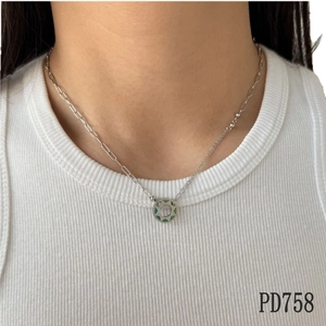 Asymmetric stainless steel necklace with green enamel doughnut pendant on model