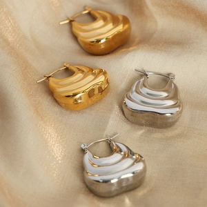 Layered wavy gold and silver titanium steel earrings on elegant champagne silk fabric