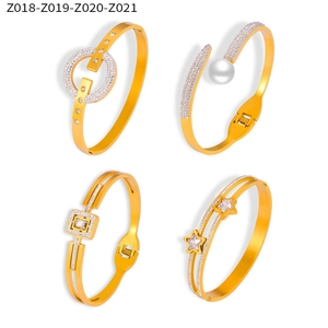 Detail view of four gold-plated hollow bangles with rhinestones and pearl accents