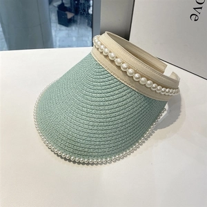Detailed close-up of mint green straw sun visor with elegant white pearl trim