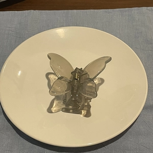 Close-up of a translucent grey butterfly hair claw clip with a gold metal spring mechanism