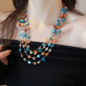 Detail of multilayer necklace with irregular orange, blue, and beige shell beads