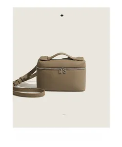 Detailed view of the dual-zipper closure and textured leather on this taupe crossbody bag
