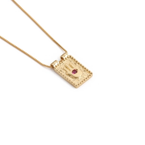 Collana con ciondolo rettangolo mano di Hamsa placcata oro con pietra rossa su sfondo bianco