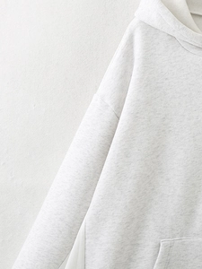 Macro detail of the light gray knit texture and stitching on a casual hooded sweatshirt