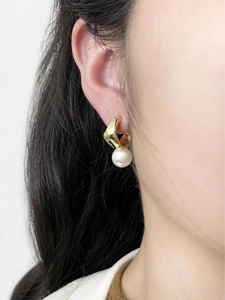 Gros plan détaillé d'une boucle d'oreille dorée avec perle blanche sur un modèle