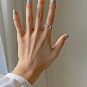 Detailed view of silver chain link ring worn on finger with minimalist hollow design