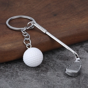 Close-up of silver metal golf club and white golf ball keychain with metallic ring
