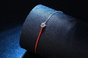 Close-up of S925 silver moissanite bracelet with red cord and polished metal chain