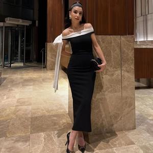 Detailed close-up of a black off-shoulder dress with a large white satin bow decoration