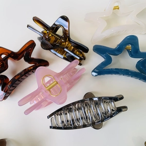 Flat lay of colorful hollow star and butterfly acrylic hair claws with gold springs