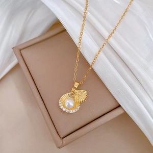 Détail du collier doré avec pendentif coquillage, perle centrale et cristaux brillants