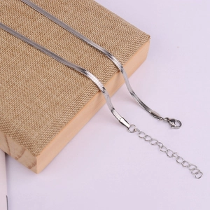 Close-up of silver stainless steel snake chain necklace with lobster clasp on a linen box